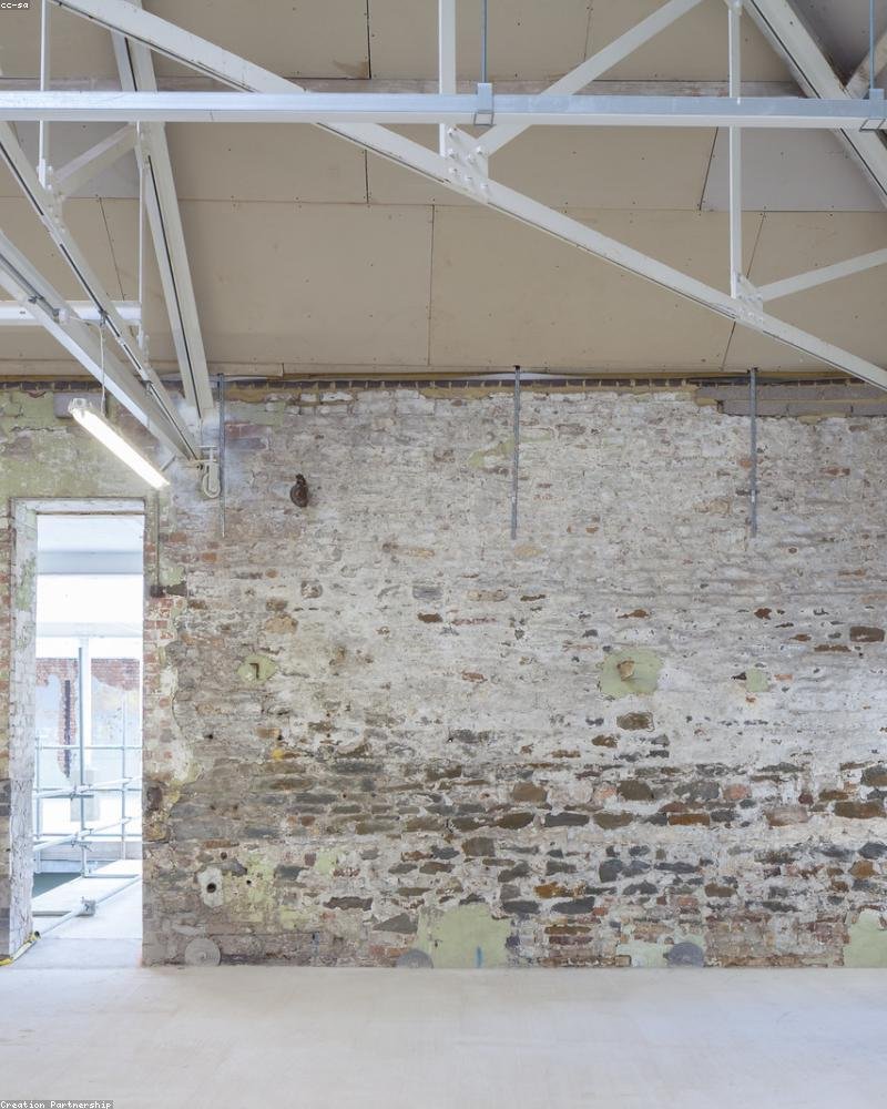 Interior of a mid-renovation Ottawa home showing exposed masonry, new structural steel and fresh concrete — a general-contracting project in progress
