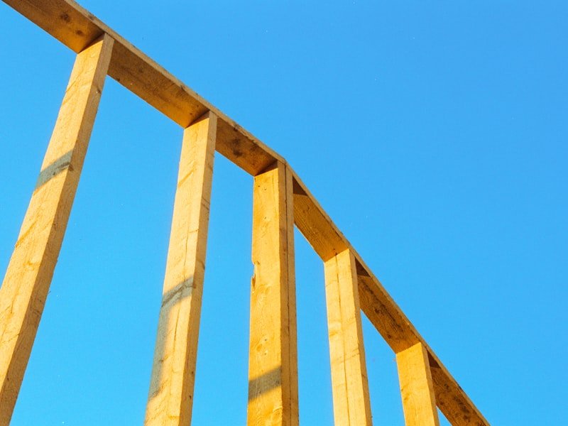 Wooden stud framing of a home addition against a bright blue sky — the early structural stage of an Ottawa home extension