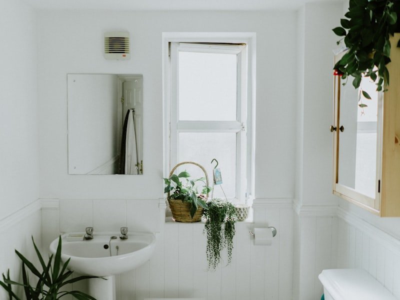 Bright, renovated bathroom with pedestal sink, sash window, mirror and white wainscoting — a contemporary Ottawa bathroom remodel