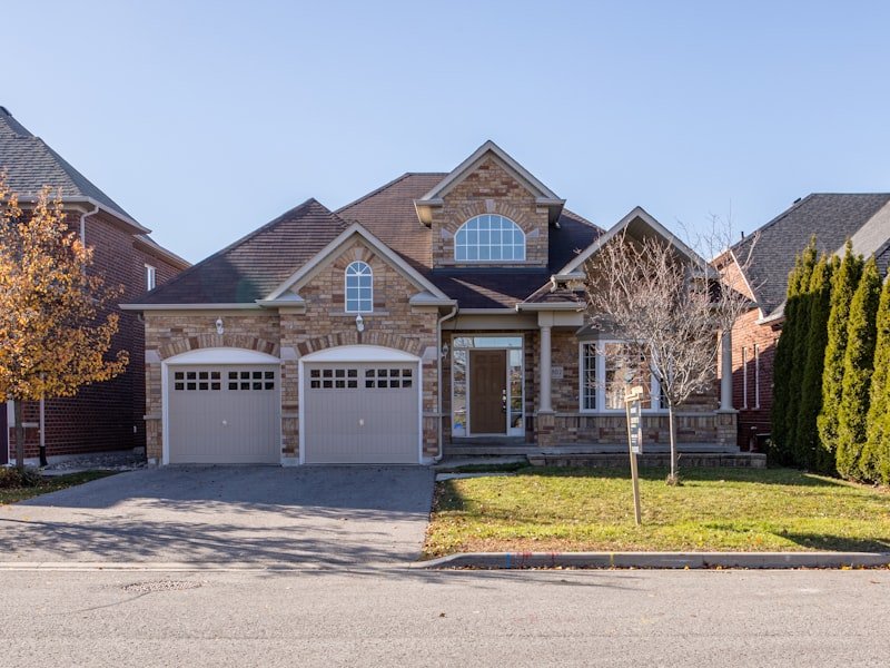 Two-storey Ontario suburban home with brick facade, twin garages, arched feature window and gabled roof — a finished exterior renovation